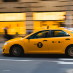 Yellow taxi driving on a street.