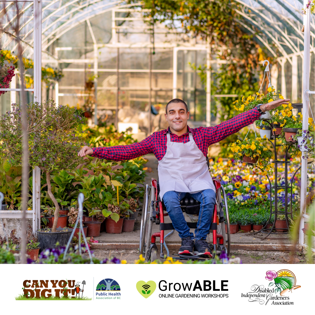 Individual sitting in a wheelchair holds their hands out open by their sides, inside of a greenhouse.