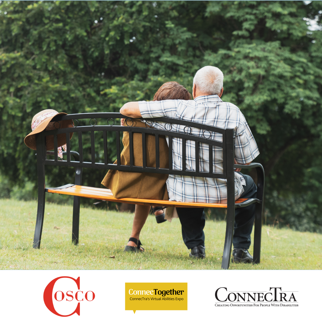 A senior couple sits on a bench outside, the man's arm around the woman's.